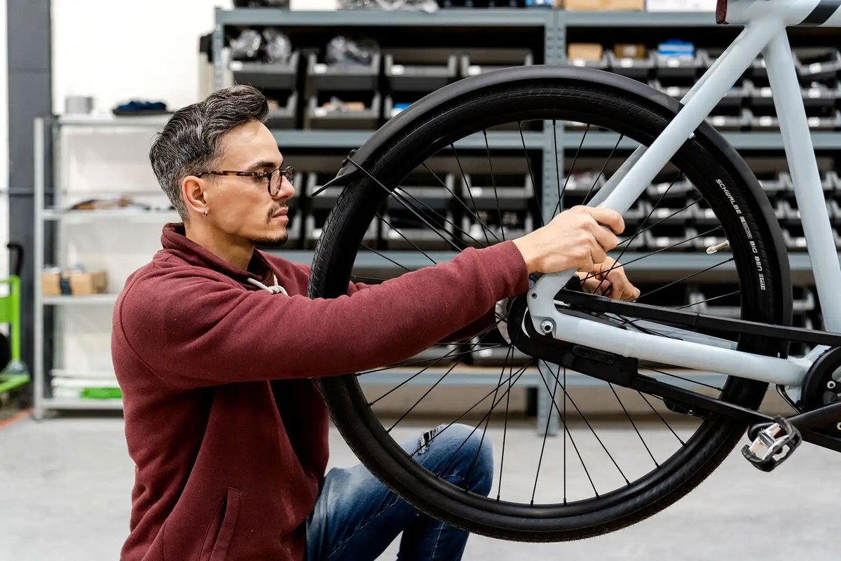 technicien contrôlant la roue arrière d'un vélo électrique reconditionné en atelier
