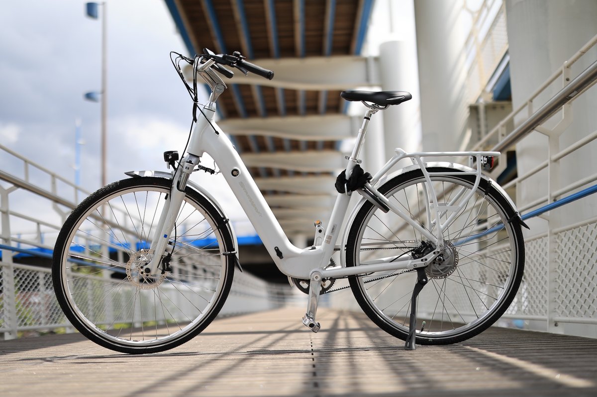 Vélo à assistance électrique urbain blanc à cadre ouvert stationné sur une passerelle, illustrant la saturation du marché du vélo en France