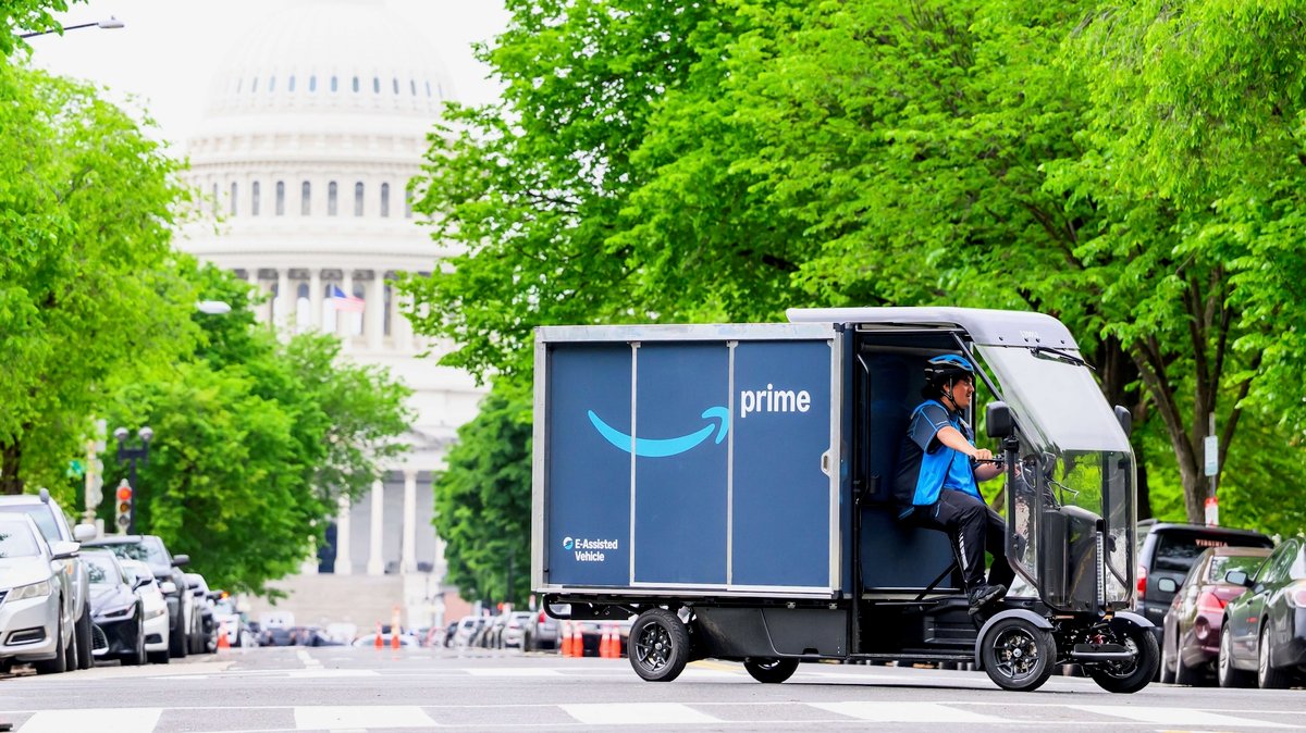 Livreur Amazon sur un vélo-cargo électrique bleu devant le Capitole à Washington.