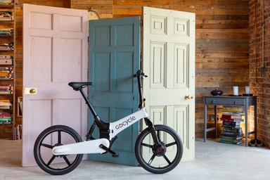 Boutique ou stand GoCycle présentant un vélo électrique pliant haut de gamme, dans un environnement urbain moderne