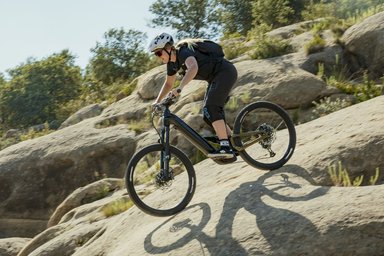 Femme en VTT électrique Haibike Alltrail descendant une piste de montagne rocailleuse