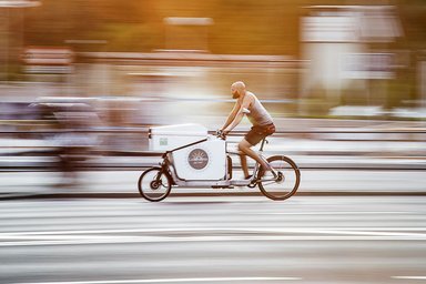 Homme roulant sur un vélo-cargo électrique de livraison éligible aux aides CEE 2025