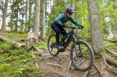 VTT électrique tout-suspendu Decathlon en promotion, pilote descendant un sentier technique en forêt
