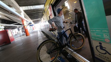 Un homme monte avec son vélo de ville dans un train TER à quai.