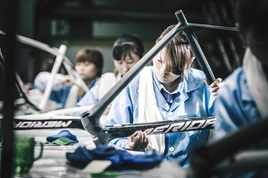 Une ouvrière examine avec précision un cadre de vélo Merida dans une usine d'assemblage.