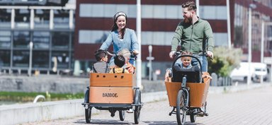 Deux parents circulant avec des enfants à bord de vélos-cargo Babboe