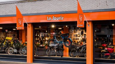 Vitrine d'un magasin La Souris aux Pays-Bas avec fatbikes et scooters électriques exposés derrière la baie vitrée
