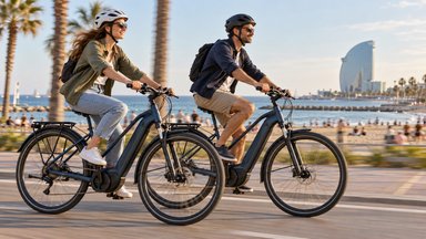 Un homme et une femme casqués roulent à vélo électrique sur la promenade en bord de mer de Barcelone
