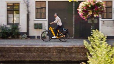 Velo de Ville AEB Pro 2027 en cadre Diamant coloris Mellon Yellow, roulant le long d'un canal