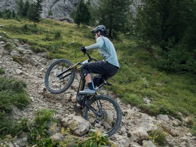 Cycliste casque sur un VTT electrique Giant en wheeling dans une montee rocailleuse de montagne