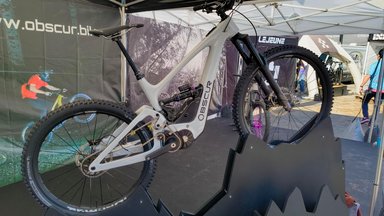 VTT électrique blanc Obscur ENYX avec moteur central et boite de vitesses integree, expose sur un stand de salon