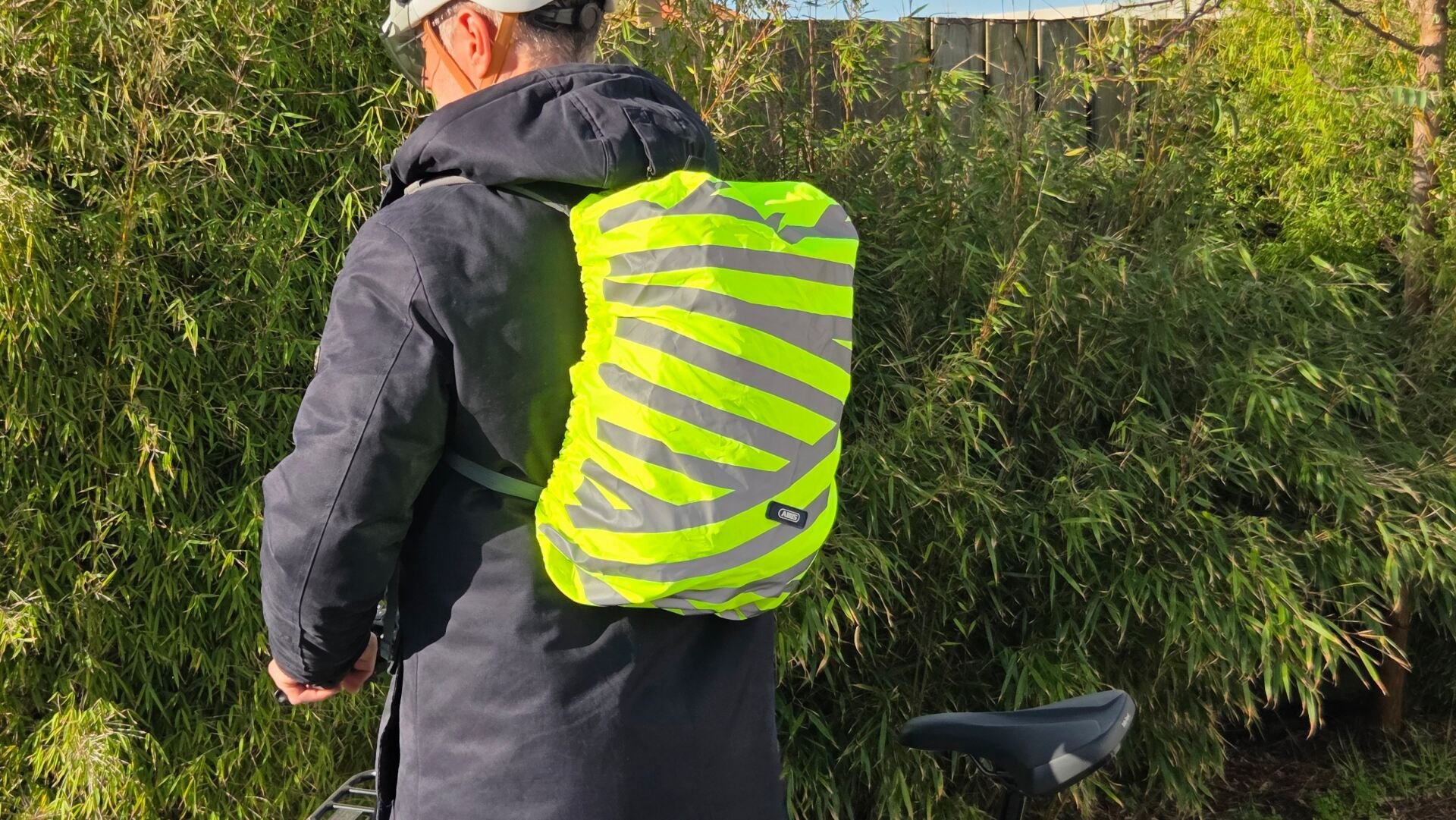 Housse de sac à dos Abus Lumino Urban X-Cover jaune fluo montée sur un sac en usage vélo urbain
