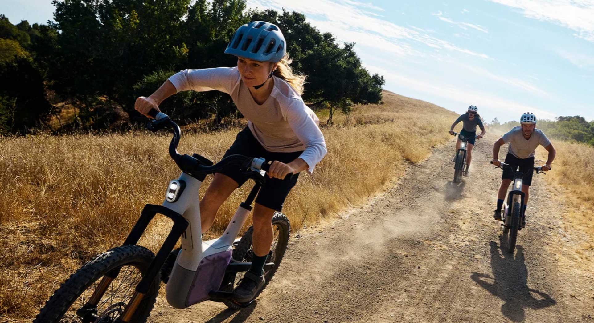 Trois cyclistes utilisent le vélo électrique Also TM-B sur un chemin, modèle futuriste développé par Rivian.
