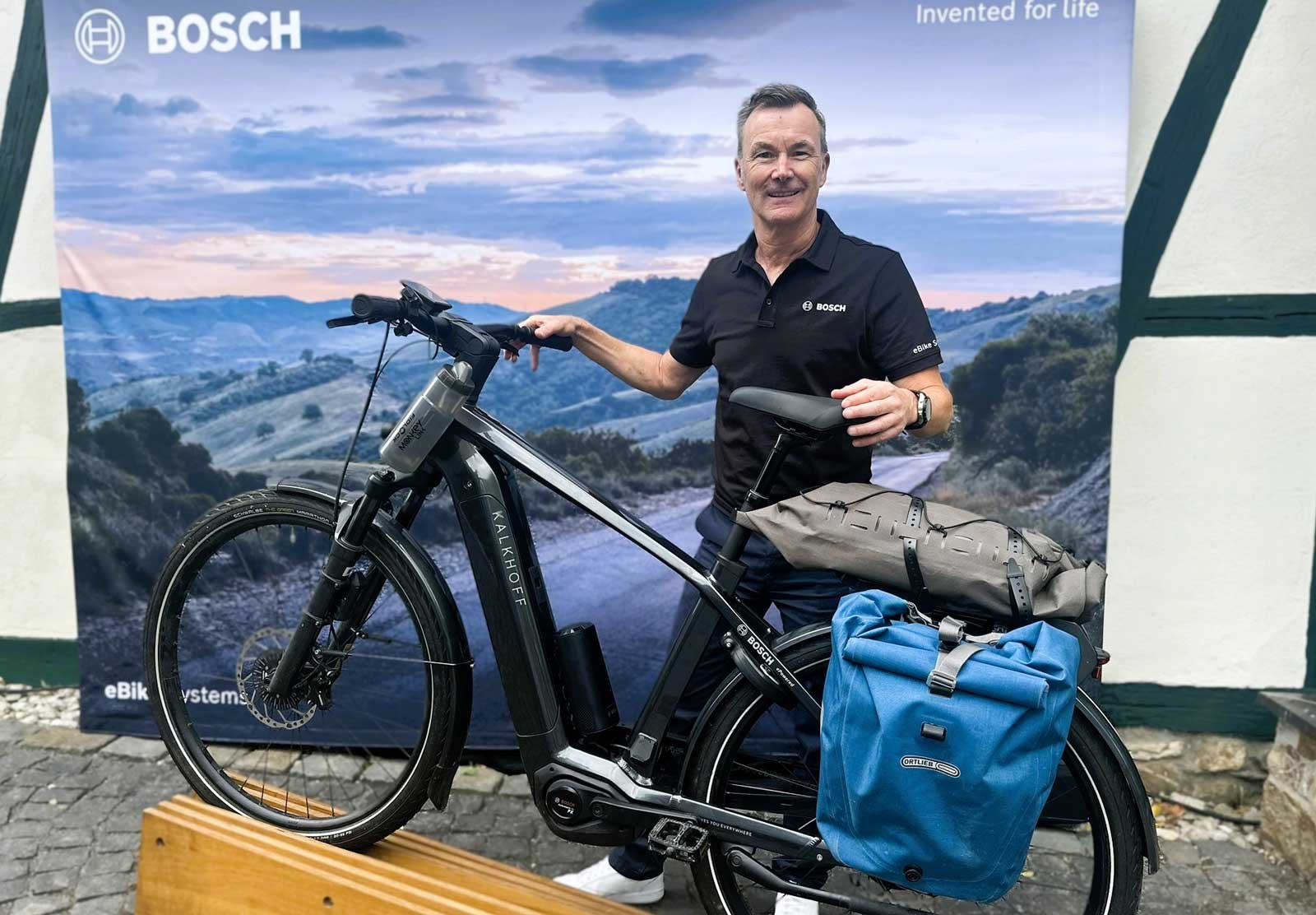 Claus Fleisher de chez Bosch présente un vélo électrique Kalkhoff équipé pour le voyage devant un stand.