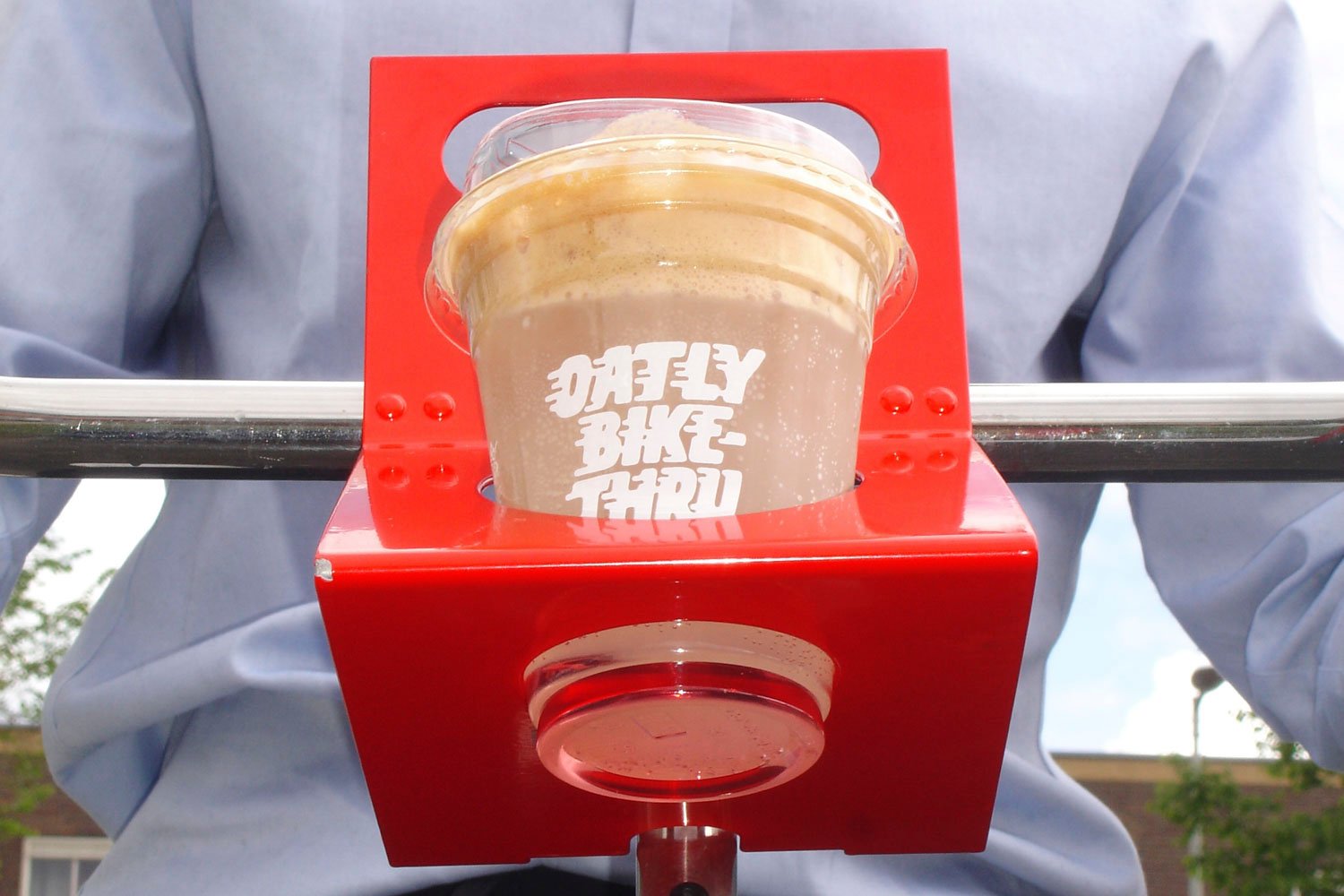 Gobelet de boisson Oatly sur un support de guidon de vélo pour le drive-thru cycliste.