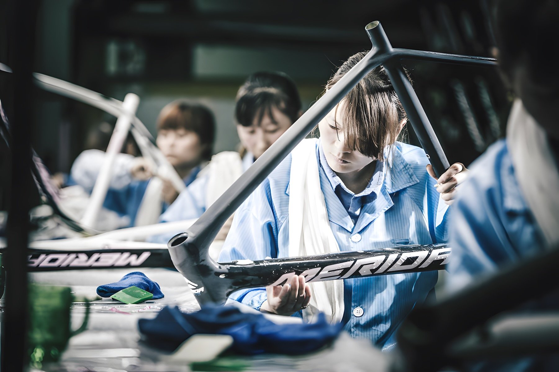 Une ouvrière examine avec précision un cadre de vélo Merida dans une usine d'assemblage.