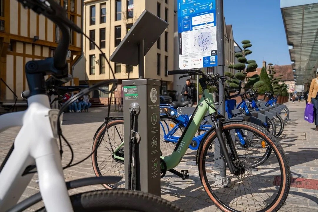 Borne antivol V-Lock sécurisant un vélo électrique vert de la marque Ellipse dans la rue.