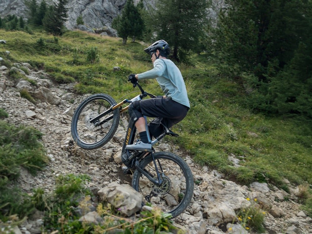 Cycliste casque sur un VTT electrique Giant en wheeling dans une montee rocailleuse de montagne