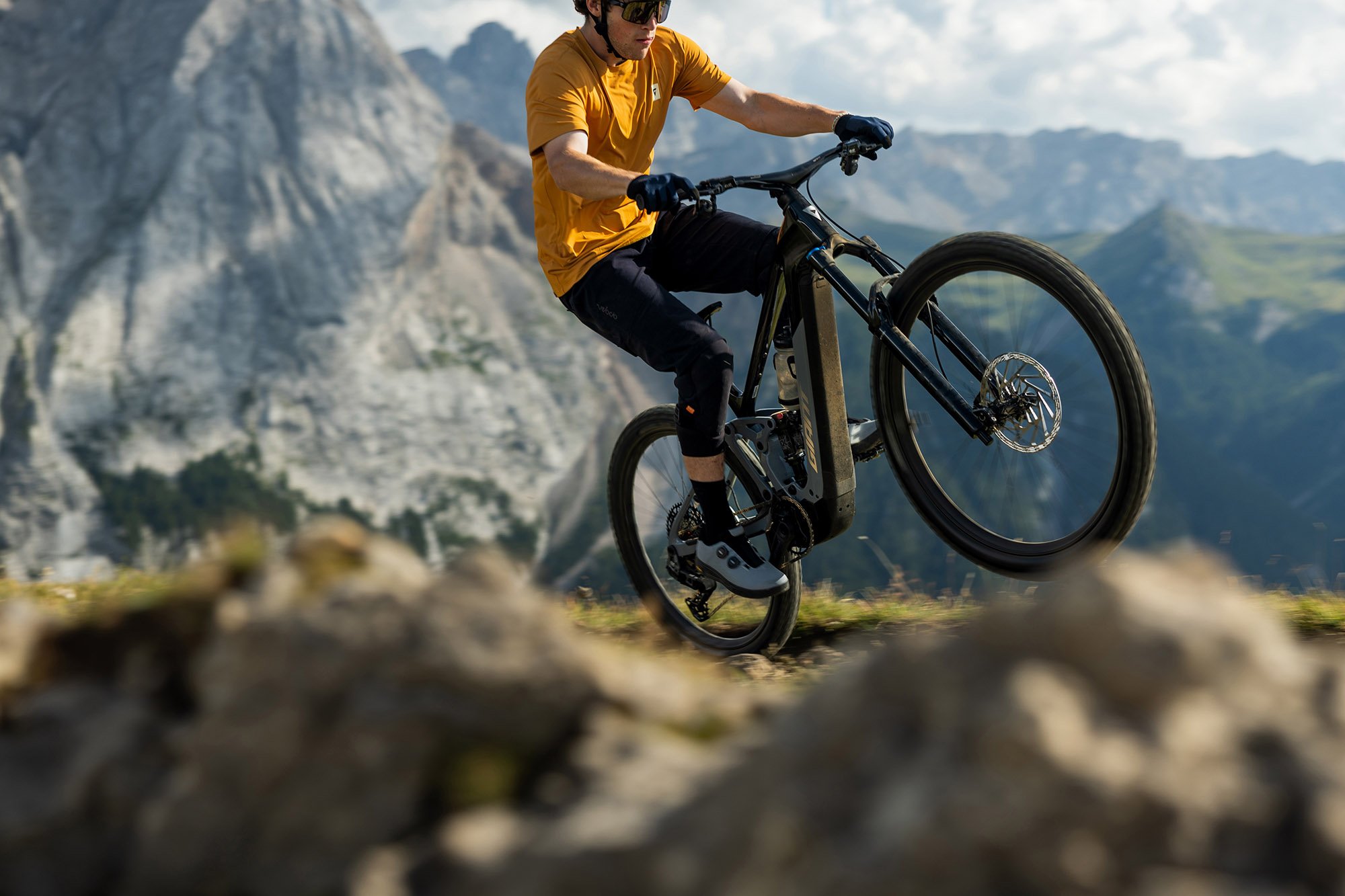 Giant Trance Advanced E+ 1 en Carbon/Tactical Grey cabré sur un rocher en montagne