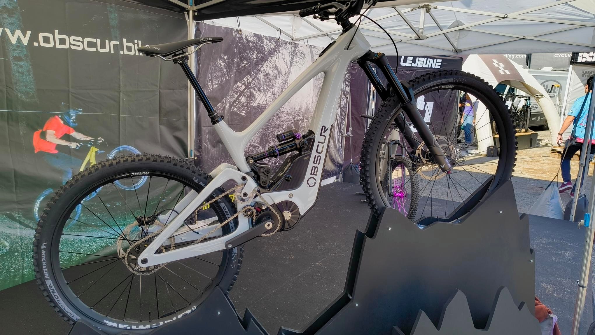 VTT électrique blanc Obscur ENYX avec moteur central et boite de vitesses integree, expose sur un stand de salon