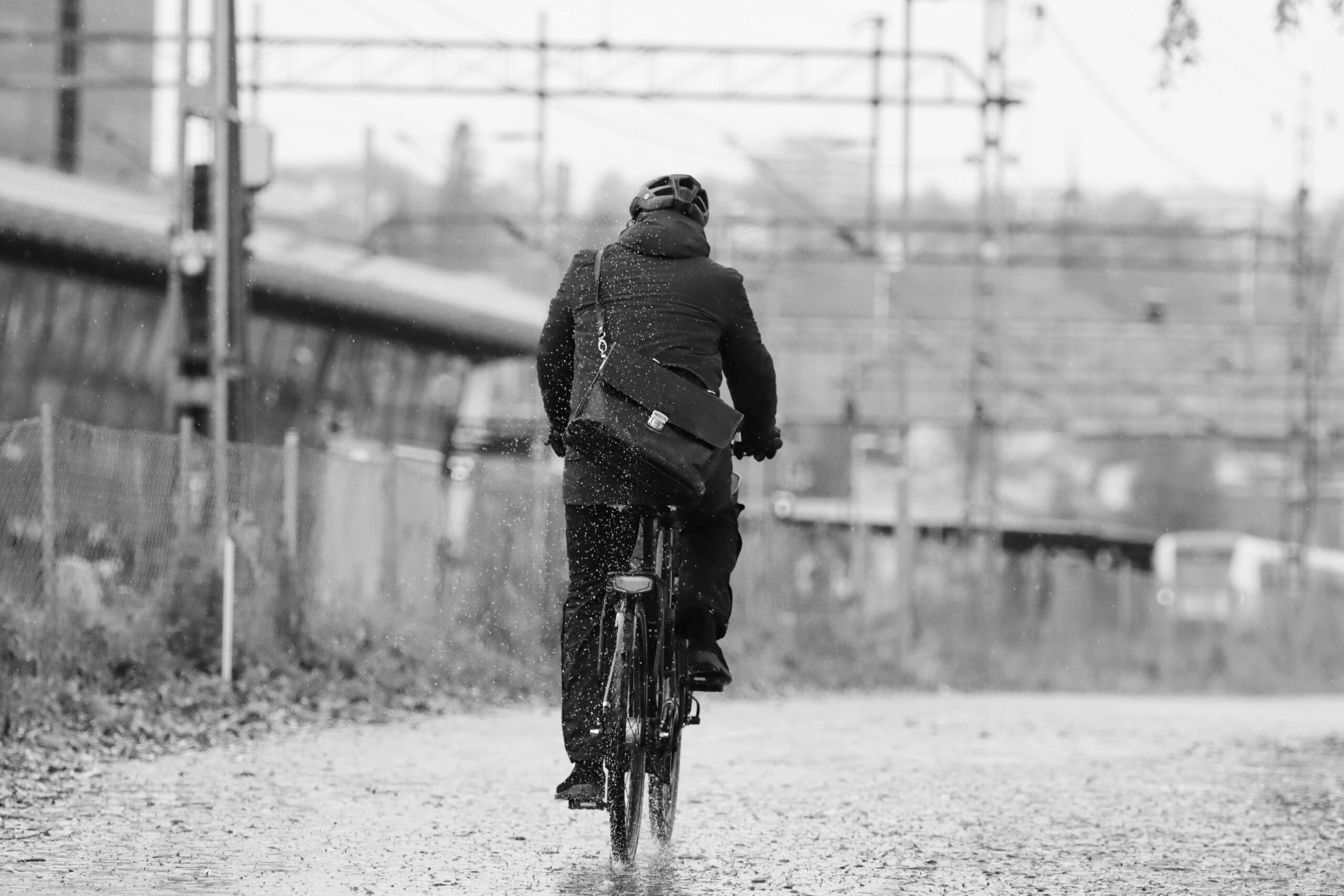 Cycliste en vélotaf sous la pluie en automne, équipé d’une veste imperméable, d’un casque et d’une sacoche