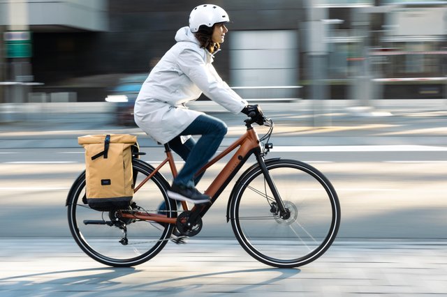 Vélo électrique Decathlon Elops LD 500E, modèle urbain avec cadre haut (ou cadre bas), porte-bagages, garde-boue, pneus à bandes réfléchissantes et freins à disque hydrauliques, conçu pour les trajets quotidiens longue distance en ville.