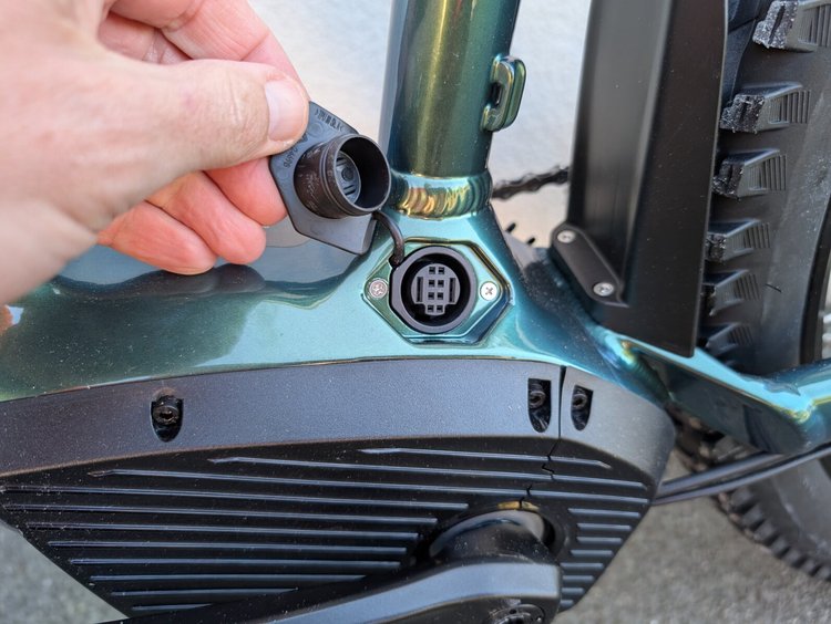 Gros plan sur le port de recharge de la batterie intégrée du VTT électrique Rockrider E-EXPL 700, protégé par un cache.