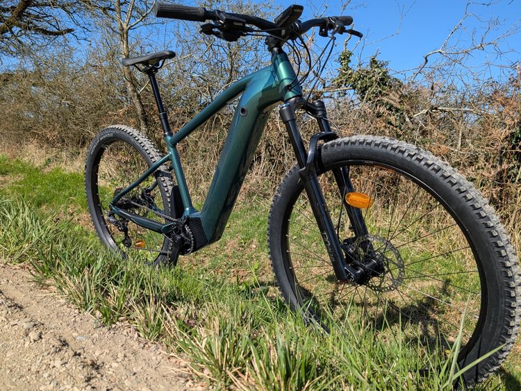 Le VTT électrique Rockrider E-EXPL 700 bleu/vert en test sur un sentier, un des meilleurs VTTae de 2025 pour la randonnée.