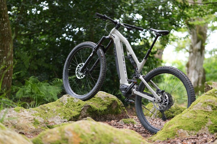 Vue de profil du VTT électrique tout-suspendu Rockrider E-FEEL 700 S dans un décor de forêt, un des meilleurs modèles 2025.