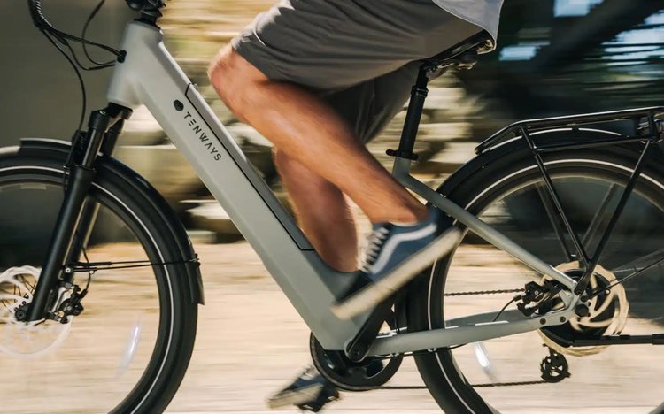 Vélo électrique Tenways Wayfarer bleu avec cadre bas, éclairage avant et feu arrière allumé, typé cruiser