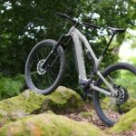 Vue de profil du VTT électrique tout-suspendu Rockrider E-FEEL 700 S dans un décor de forêt, un des meilleurs modèles 2025.